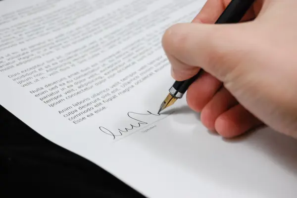 Mano firmando un contrato con pluma estilográfica