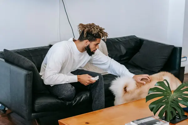 Hombre acariciando a su perro en el sofá