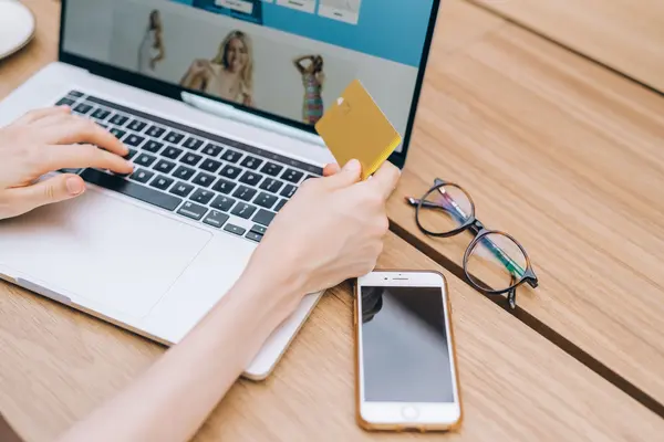 Mano con tarjeta ante el portátil